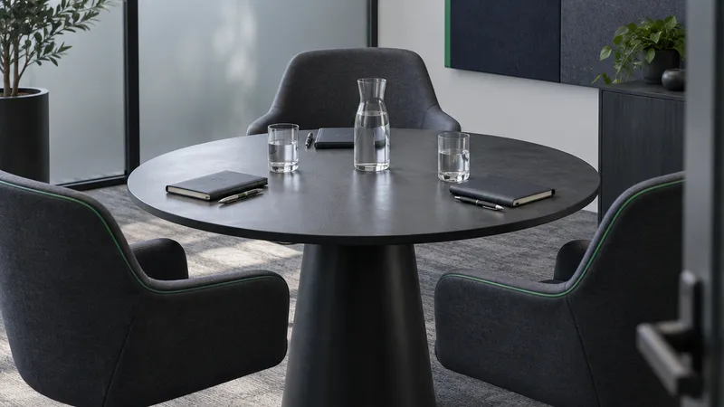 A quiet glass-walled meeting room set with a water carafe and glasses around a round table