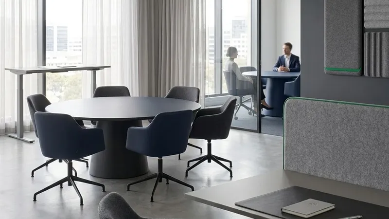 Dark lounge armchairs and acoustic wall panels in a quiet office breakout space